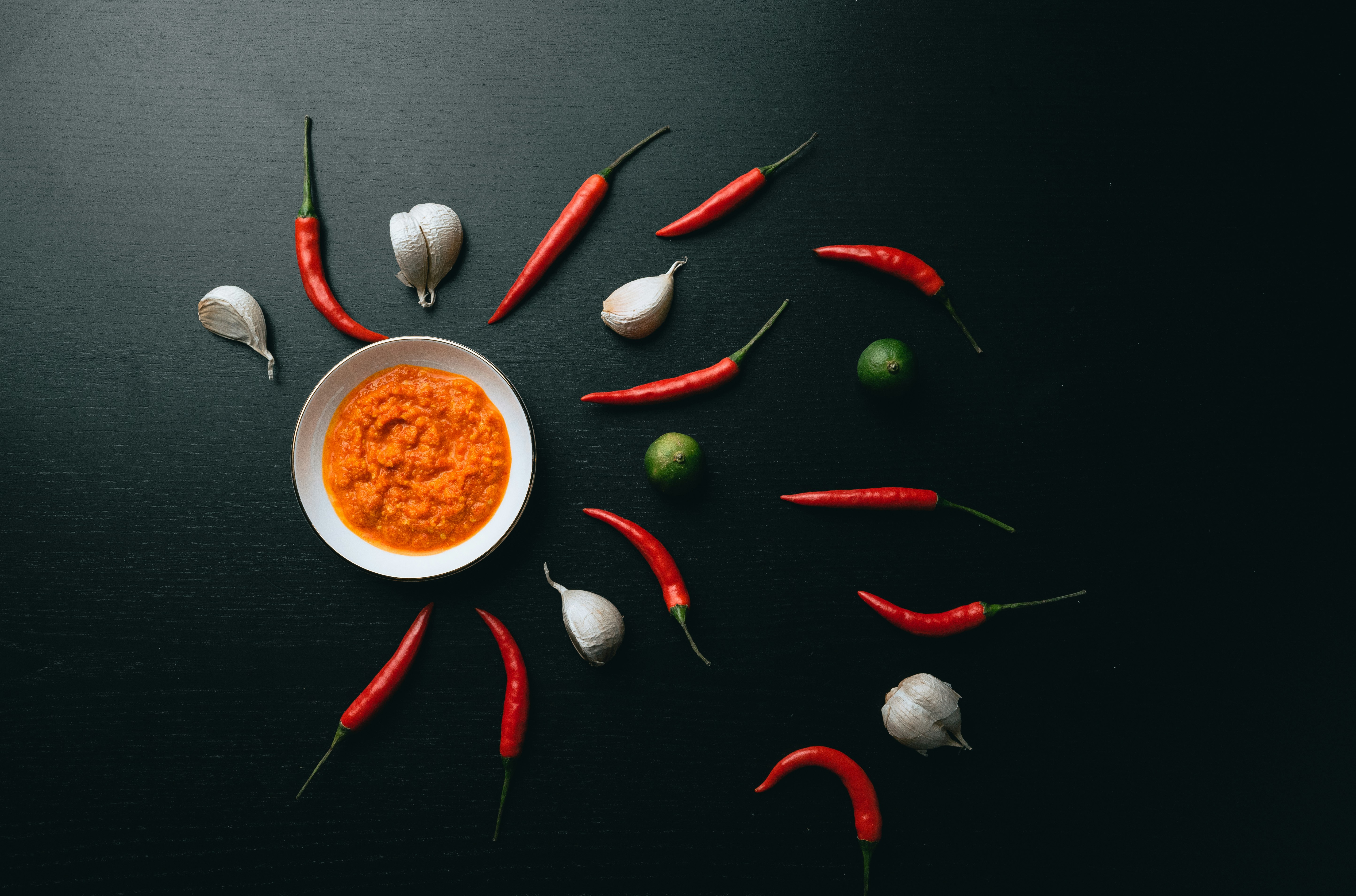 red chili pepper and green chili on white ceramic bowl